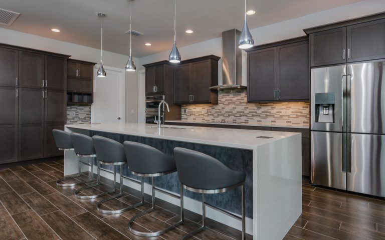 Contemporary kitchen with grey wood custom cabinets and waterfall edge quartz island countertop