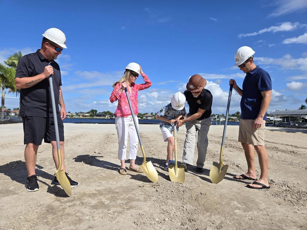 Jim Aubuchon helps a young boy dig during a groundbreaking ceremony.