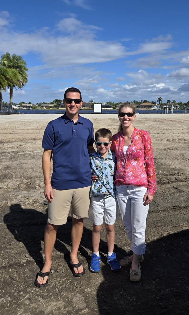 Young family poses for a photo in front of their new homesite.